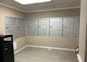 Thumbnail 25 of 26 - A room with a wall of mailboxes and a trash can.