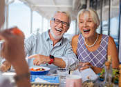 Thumbnail 2 of 38 - an older man and woman sitting at a table eating food