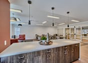 Thumbnail 29 of 32 - A modern kitchen with a large island and pendant lights.