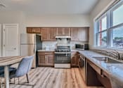 Thumbnail 3 of 32 - A kitchen with wooden cabinets and a grey chair.