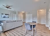 Thumbnail 5 of 32 - A living room with a grey couch and a wooden dining table.