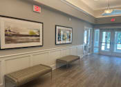 Thumbnail 6 of 7 - A hallway with two benches and two framed pictures on the wall.