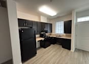 Thumbnail 27 of 30 - A kitchen with black appliances and cabinets.