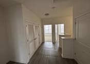 Thumbnail 26 of 30 - A long hallway with white walls and wood floors.
