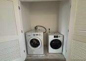 Thumbnail 20 of 30 - Two white front load washing machines in a small laundry room.