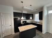 Thumbnail 6 of 30 - A kitchen with black cabinets and a granite countertop.