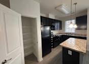 Thumbnail 5 of 30 - A kitchen with black cabinets and a granite countertop.