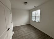 Thumbnail 8 of 30 - A room with a wooden floor and a window with blinds.