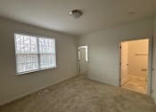 Thumbnail 13 of 30 - A room with a window, two doors, and a carpeted floor.