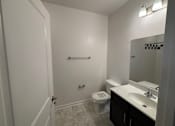 Thumbnail 17 of 30 - A bathroom with a toilet, sink, and mirror.