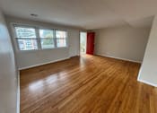 Thumbnail 10 of 29 - A room with wooden flooring and a red door.