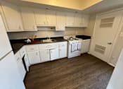 Thumbnail 15 of 29 - A kitchen with white cabinets and a black countertop.