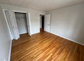 Thumbnail 18 of 29 - A room with wooden flooring and two doors, one open and one closed.