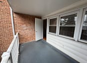 Thumbnail 29 of 29 - A balcony with a brick wall and a white door.