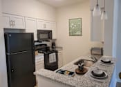 Thumbnail 9 of 54 - a kitchen with a granite counter top and a black refrigerator