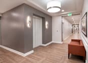 Thumbnail 20 of 54 - a hallway with a couch and a chair and a corridor with doors