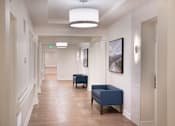 Thumbnail 40 of 54 - a hallway with blue chairs and white walls and a wood floor