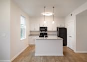 Thumbnail 31 of 54 - a kitchen with white cabinets and a white island with a black refrigerator