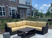Thumbnail 7 of 7 - A yellow couch and black coffee table on a patio.