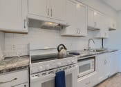Thumbnail 43 of 43 - a kitchen with white cabinets and a stove and a sink