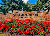 Thumbnail 6 of 29 - A sign that says Woodcliffe Manor Apartments in front of a brick wall.