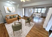 Thumbnail 1 of 29 - A living room with a couch, chairs, and a dining table.