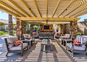 Thumbnail 34 of 41 - A patio with a stone fireplace and a wooden pergola.