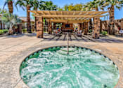 Thumbnail 11 of 41 - A hot tub in the middle of a patio with a pergola above it.