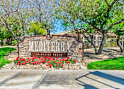 Thumbnail 5 of 41 - The entrance to Mediterra Apartments is surrounded by red flowers and greenery.
