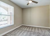 Thumbnail 28 of 41 - A room with a ceiling fan and carpeted floor.