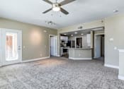 Thumbnail 8 of 41 - A spacious living room with a ceiling fan and a kitchen area in the background.