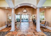 Thumbnail 7 of 41 - A hallway with a tiled floor and columns on either side.