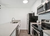 Thumbnail 10 of 18 - A modern kitchen with a black refrigerator, stove, and microwave.