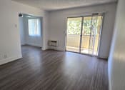 Thumbnail 2 of 23 - Spacious living room with wood-style floors and sliding glass doors to private patio