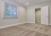 Thumbnail 14 of 23 - A large room with a carpeted floor and a window with blinds.