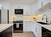 Thumbnail 6 of 18 - A kitchen with white cabinets and a black oven.