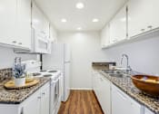 Thumbnail 5 of 24 - A kitchen with granite countertops and white cabinets.