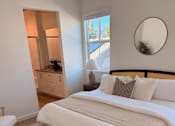 Thumbnail 10 of 27 - A bedroom with a large bed and a striped rug.