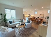 Thumbnail 2 of 27 - A living room with a grey couch, a wooden table, and a dining table with chairs.