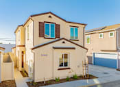 Thumbnail 18 of 27 - A beige house with a brown roof and a blue garage door.