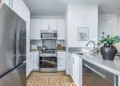 Thumbnail 19 of 27 - A modern kitchen with a stainless steel refrigerator and white cabinets.