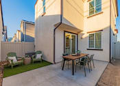 Thumbnail 16 of 27 - A patio with a table and chairs is in front of a house.