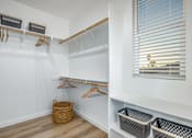 Thumbnail 23 of 27 - A white closet with a window and a basket on the floor.