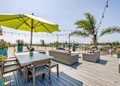 Thumbnail 5 of 18 - A wooden table with chairs and a yellow umbrella on a wooden deck.
