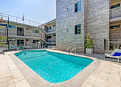 Thumbnail 1 of 18 - A swimming pool in a courtyard surrounded by buildings.