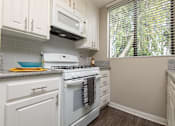 Thumbnail 31 of 34 - A white stove and microwave in a kitchen with white cabinets.