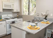 Thumbnail 2 of 34 - A kitchen with a granite countertop and white appliances.