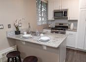 Thumbnail 30 of 34 - A kitchen with a countertop, stove, and cabinets.