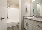 Thumbnail 24 of 34 - A bathroom with a sink, mirror, and bathtub.