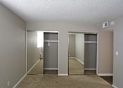 Thumbnail 13 of 34 - A room with a carpeted floor and two closets with mirrors.